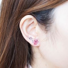 a close up of a person's ear with a flower tattoo on the side