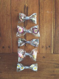 four bow ties with flowers on them hanging from a wooden wall in front of a wood paneled wall