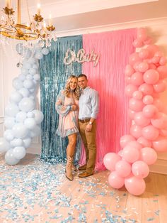 a man and woman standing next to each other in front of balloons