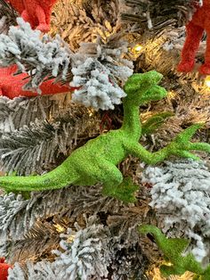 a green toy lizard sitting on top of a christmas tree