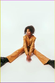 a woman sitting on the ground with her legs crossed wearing brown leather pants and black boots