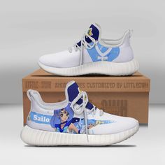 a pair of white and blue sneakers with anime characters on them, sitting in front of a cardboard box