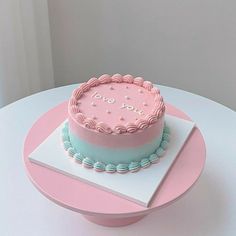 a pink and blue cake sitting on top of a white table