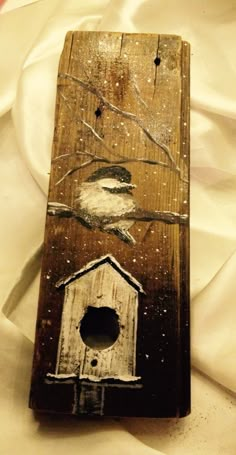 a bird sitting on top of a wooden box next to a white bed sheet and pillow