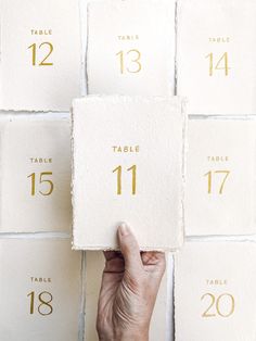 a hand holding up a piece of paper with the numbers on it in gold foil