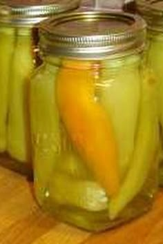 jars filled with pickles sitting on top of a wooden table