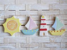 three decorated cookies sitting on top of a wooden table next to each other, one with a sailboat and the other with a smiling face