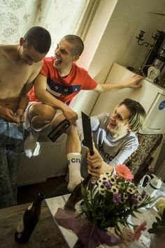 two men are sitting on a table and one man is holding a knife in his hand