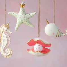 sea animals and seashells hanging from strings on a pink background with gold accents