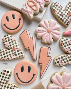 decorated cookies are arranged in the shape of smiley face and lightning bolt, with pink flowers