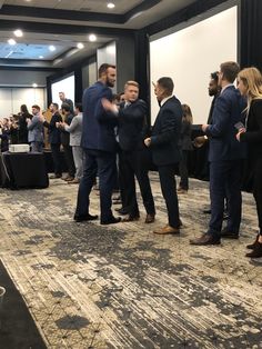 a group of men standing around each other in front of a crowd at a conference