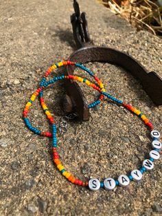 a pair of colorful beaded bracelets sitting on top of a rock next to an earphone