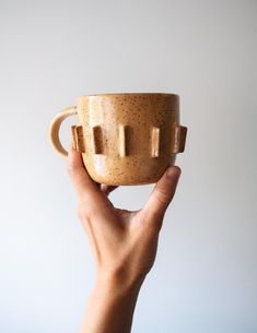 a hand holding a coffee cup with two handles