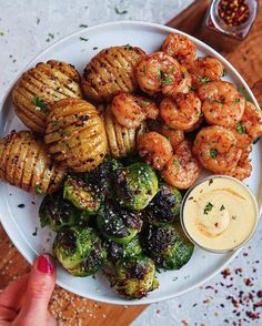 a white plate topped with grilled shrimp, brussel sprouts and potatoes