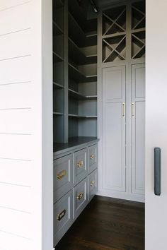 an empty walk in closet with white walls and gray drawers on both sides, along with black handles