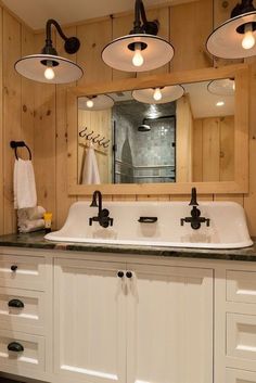 a bathroom with two sinks and three lights on the wall above it, along with other lighting fixtures