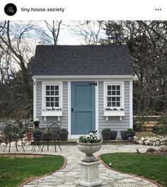 a small white house with a blue door and window on the front side, surrounded by green grass