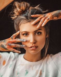 a woman with her hands painted all over her face and hand on top of her head