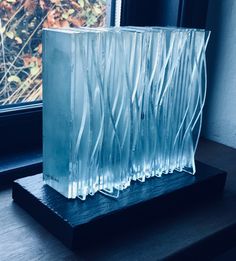 an ice block sitting on top of a wooden table next to a window sill