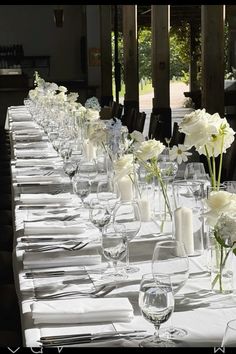 a long table is set up with white flowers and place settings for dinner guests to enjoy