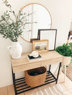 a wooden table topped with a mirror next to a potted plant and a basket