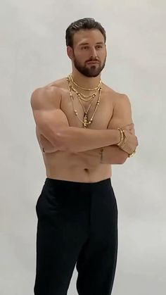 a shirtless man with his arms crossed wearing gold chains and bracelets on his chest