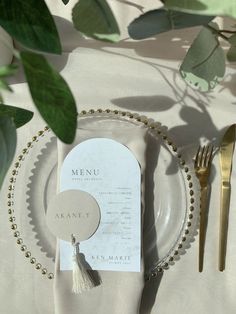 a table setting with place settings and silverware, including a menu card on a plate