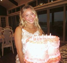 a woman standing in front of a cake with candles on it