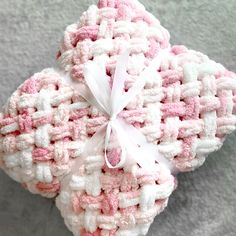 two pink and white crocheted heart shaped ornaments on a gray surface with ribbon