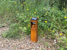 a wooden trash can sitting in the middle of a field