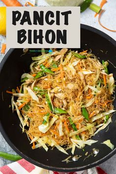 pancit bihon with shredded carrots and green onions in a black skillet