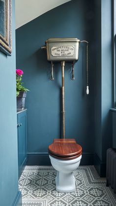 a toilet with a wooden seat in a blue bathroom next to a radiator