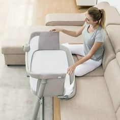 a woman sitting on top of a couch next to a baby seat