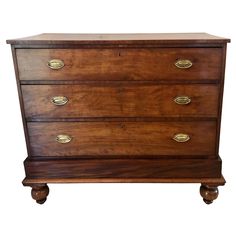 an antique chest of drawers with brass pulls and knobs on the front, against a white background