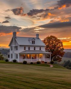 a large white house sitting on top of a lush green field under a cloudy sky