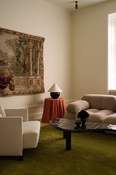 a living room filled with furniture and a painting on the wall above it's coffee table