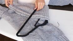 a woman is holding onto her gray knitted sweater and black ribbon on the bottom