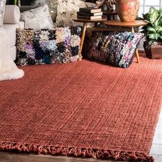 a red rug with fringes on the floor in front of a couch and coffee table