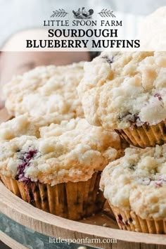 some blueberry muffins sitting on top of a wooden tray with text overlay that reads little spoon farm sourdough blueberry muffins