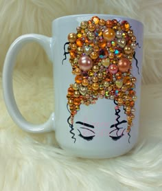 a white coffee mug decorated with beads and pearls on it's side, featuring a woman's face