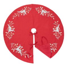 a red christmas tree skirt with white birds and holly branches on the front, tied in a knot