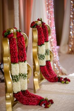 red and white flowers are arranged on gold stands