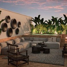 a living room filled with lots of furniture next to a wall covered in potted plants