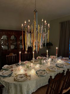 a dining room table is set with plates and candles