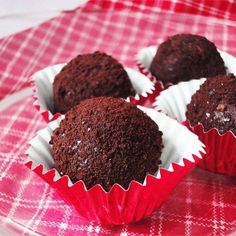 four chocolate cupcakes sitting on top of a red and white plate