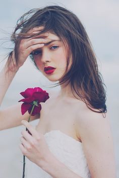 a woman holding a rose in her right hand and looking at the camera with an instagram