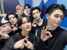 group of young men posing in front of a blue wall with their fingers up to the camera