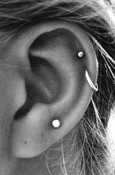 a woman's ear with three piercings on it