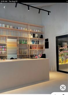 a store with shelves filled with vases and bottles on the wall next to a sink