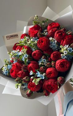 a bouquet of red roses with blue and white flowers